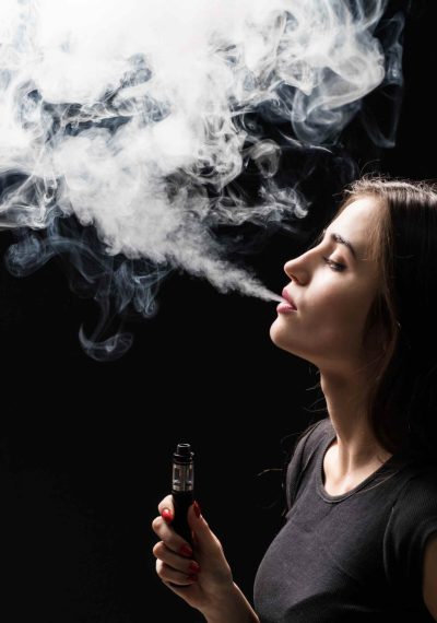 joven-y-bella-mujer-morena-fumando-vaping-cigarrillo-electronico-con-humo-en-la-pared-negra (1)
